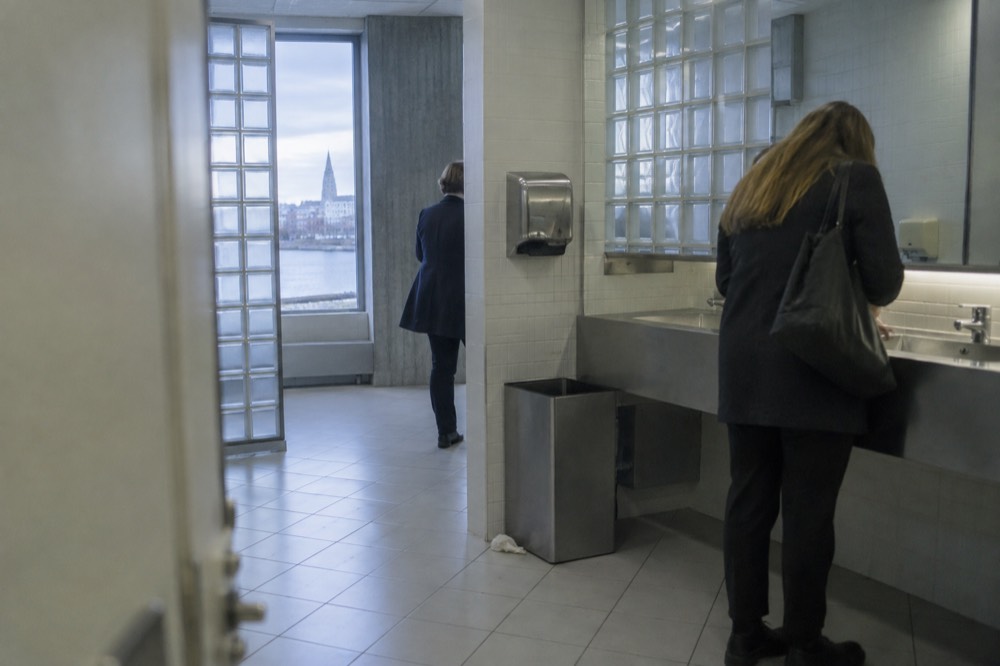 A modern public restroom interior with tiled floor, sink and hand dryer in a Reykjavik municipal building