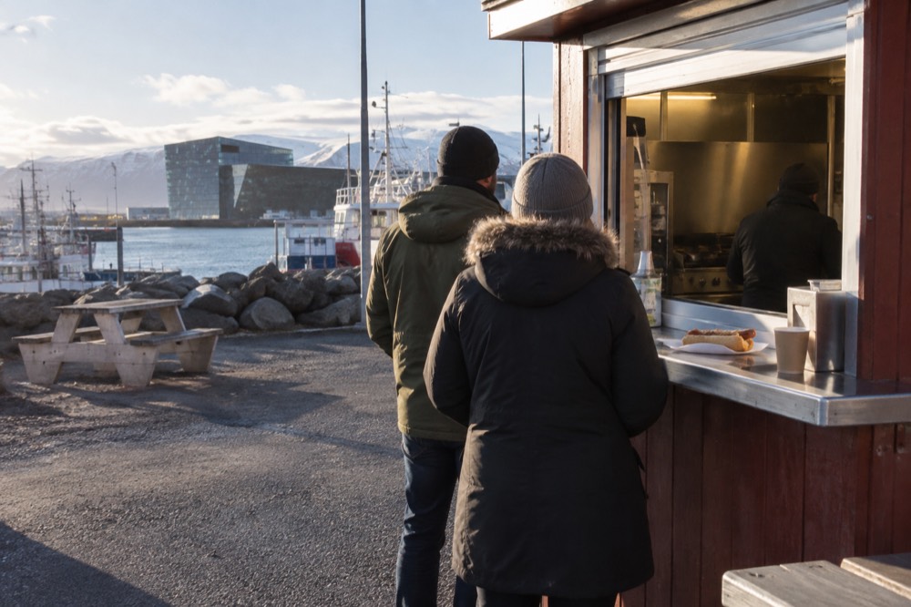 A hot dog stand beside the harbour with a short queue of customers