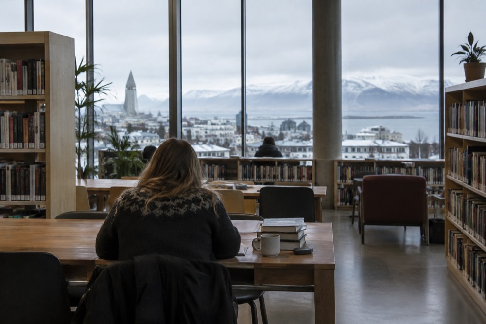 Reading room inside a Reykjavik public library with tall shelves and daylight
