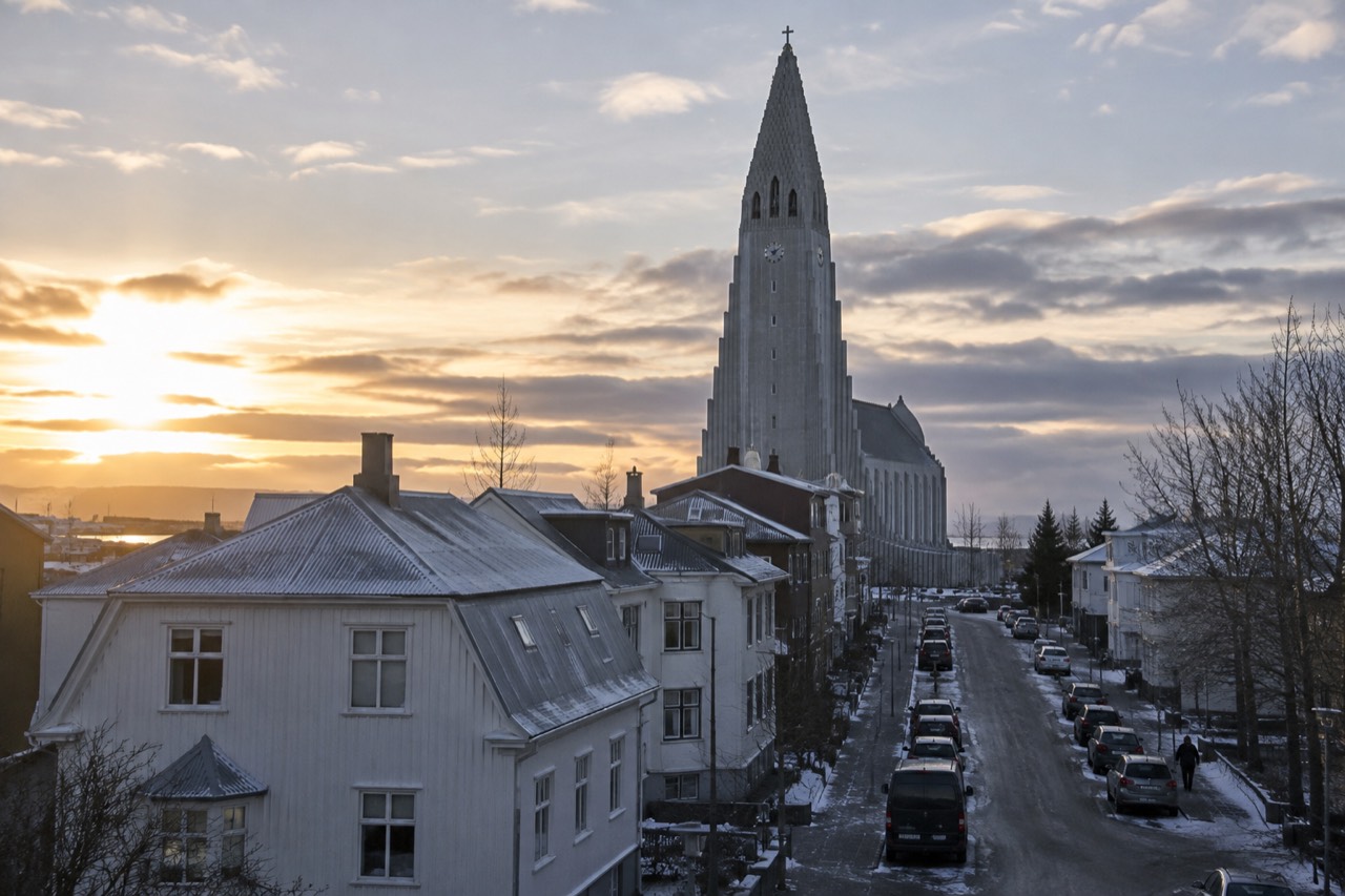 View across Reykjavik rooftops toward the Hallgrímskirkja church tower under a wide sky