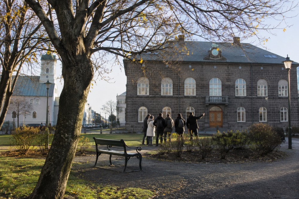 A local guide speaking to a small group of visitors gathered in an old town square in Reykjavik