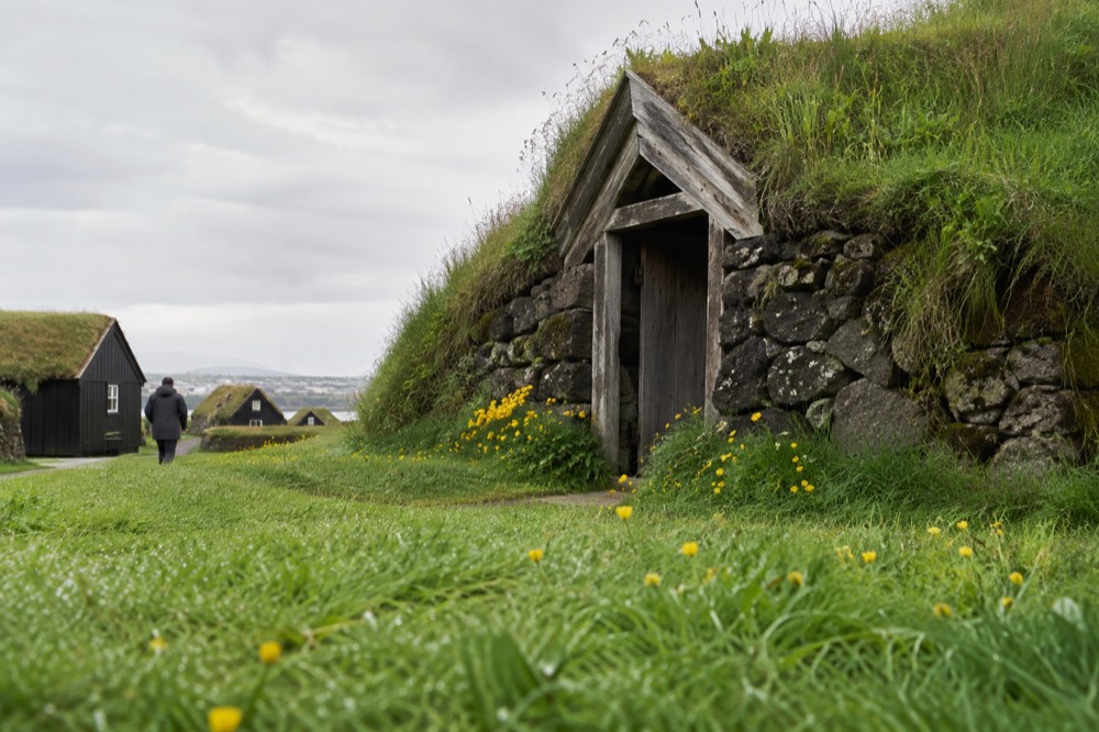 A turf-roofed stone dwelling with a grassy roof blending into a green hillside