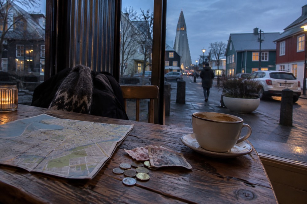 Coins and small krona notes on a wooden table beside a map of Reykjavik
