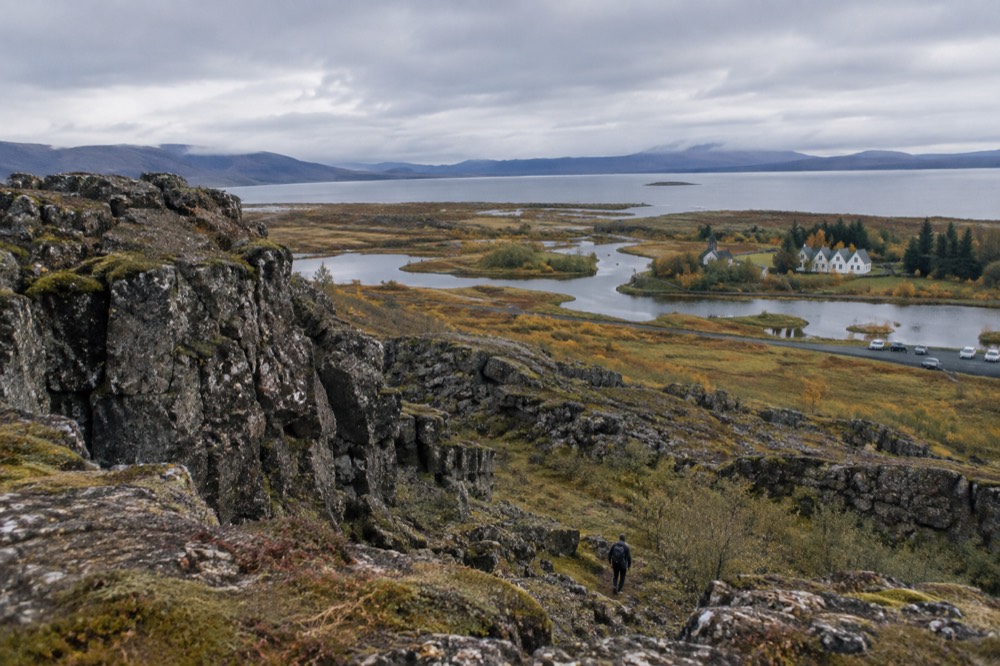 A rift valley landscape with a lake and low cliffs under cloudy light
