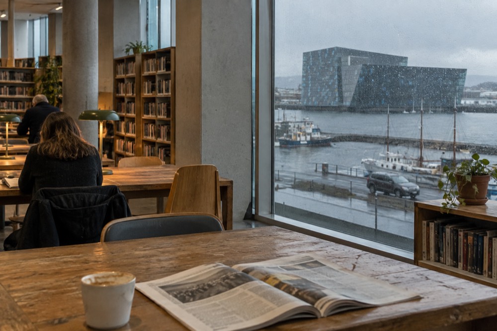 Reading room with wooden shelves and long tables in a city library