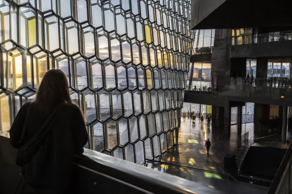 Glass facade panels catching light inside a concert hall foyer