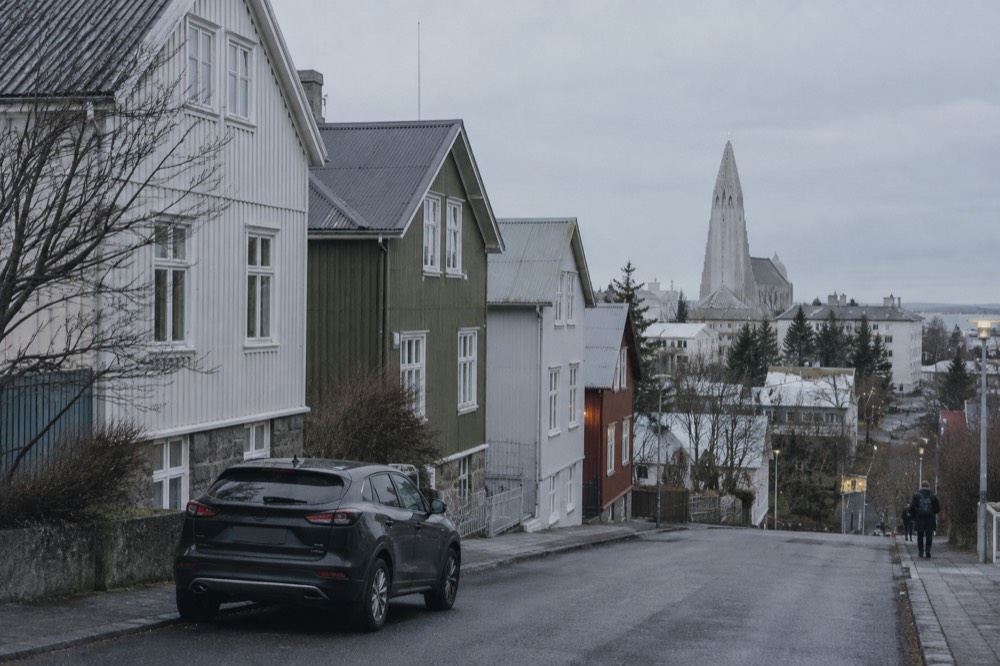Car parked on a quiet outer Reykjavik street with the city center skyline in the distance