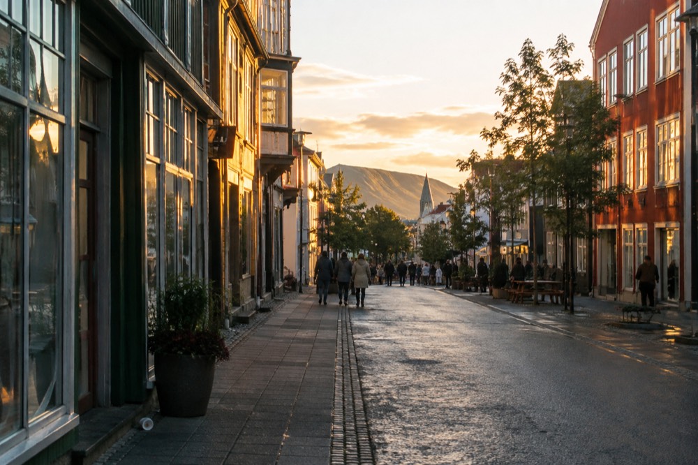 A Reykjavik street in late evening light with buildings and a distant hill under a still-bright sky