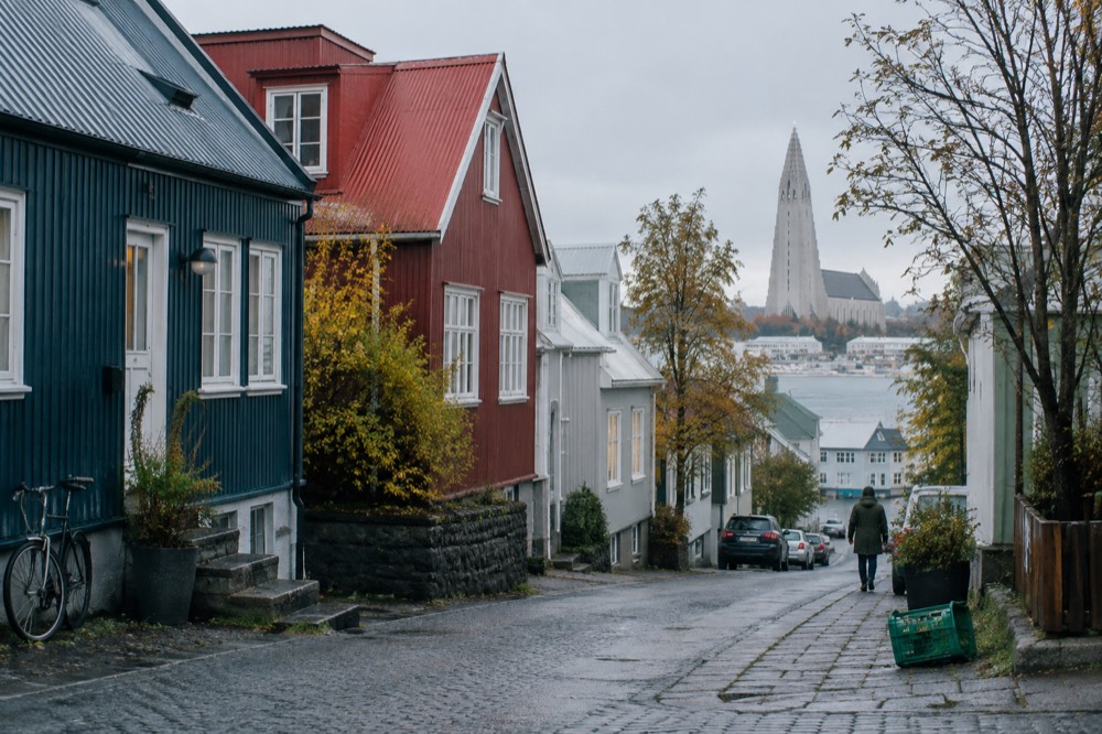 A quiet Reykjavik street with coloured houses and a church spire in the distance