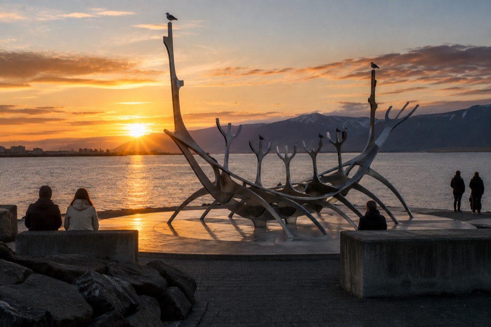 A steel boat-shaped sculpture on a coastal path with water behind it