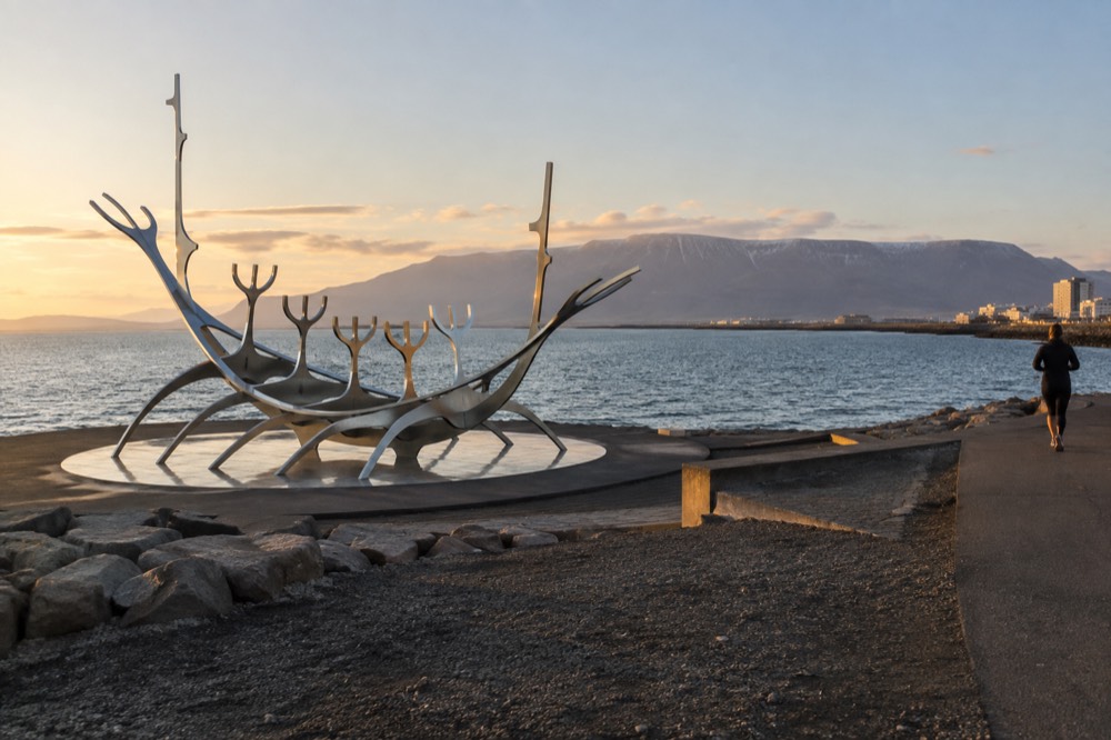 Steel Sun Voyager sculpture on the waterfront path with mountains across the water in the distance