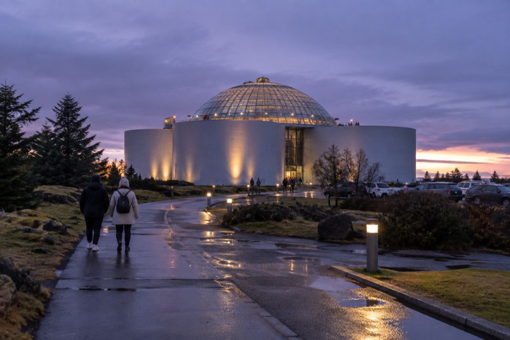 Glass dome of the Perlan building glowing in evening light above the hilltop