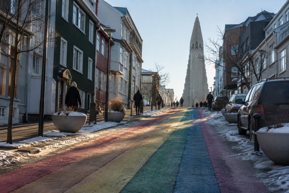 The painted rainbow stripes of Skolavordustigur street rising toward a large church in Reykjavik