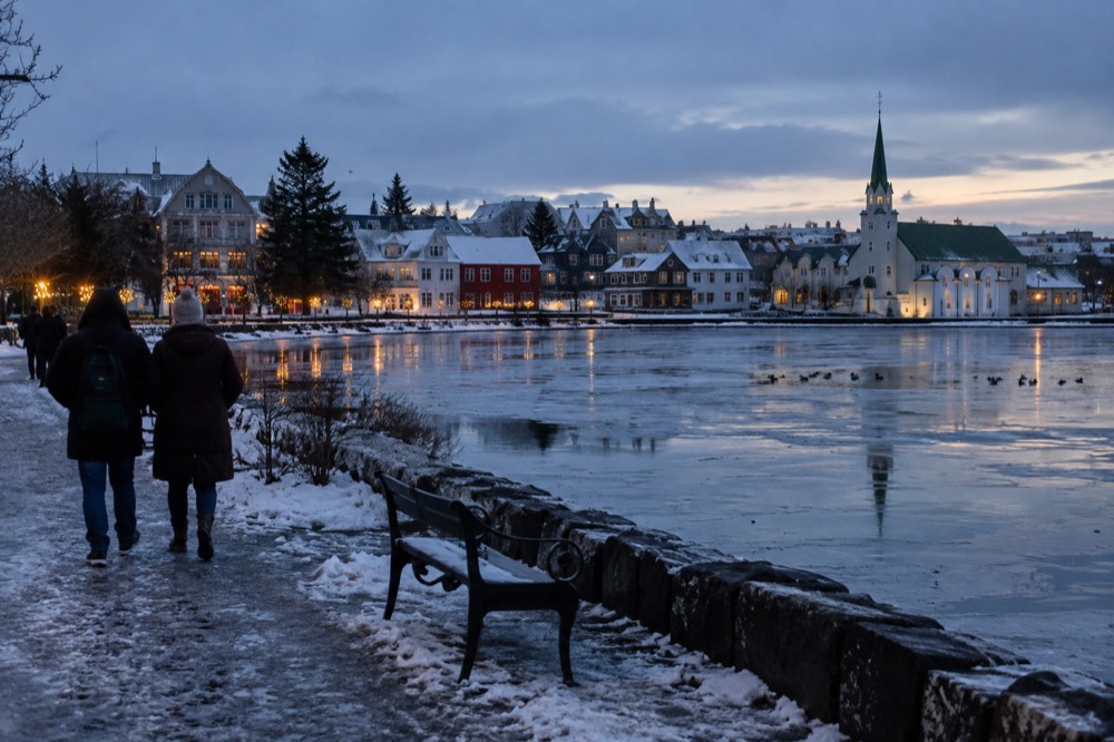 Tjörnin pond under long evening light with the old town skyline behind the water