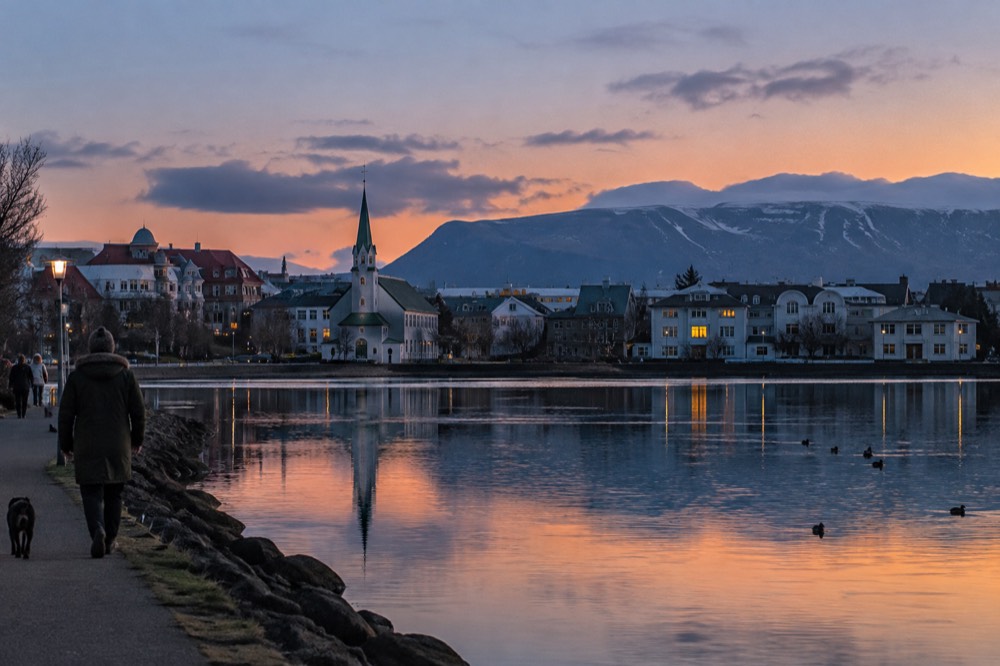 Evening view over Tjörnin pond with Reykjavik rooftops and distant mountain ridge