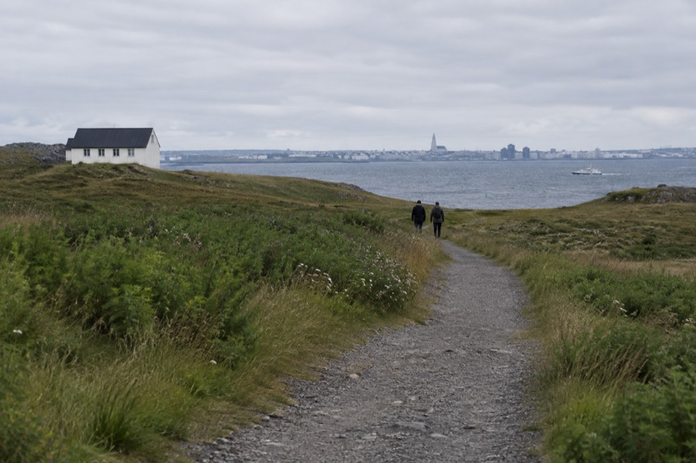 A gravel walking path crossing open grassland toward the sea on a small island